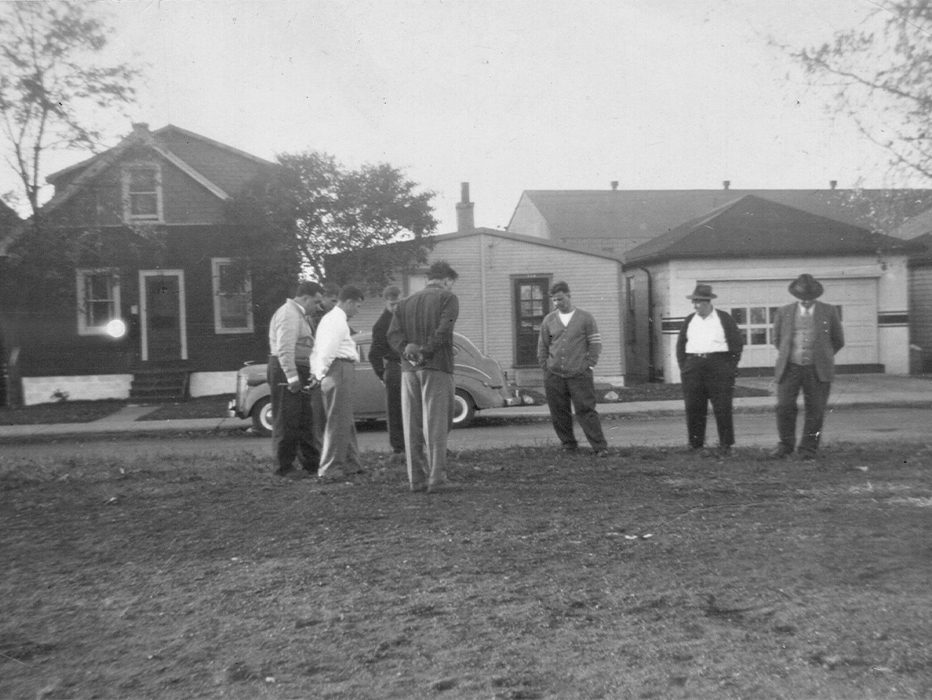 Men playing Bocce amid houses with Rocco’s Garage in background.