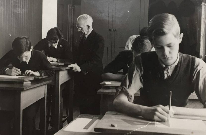 Teacher and male students tend to their studies.