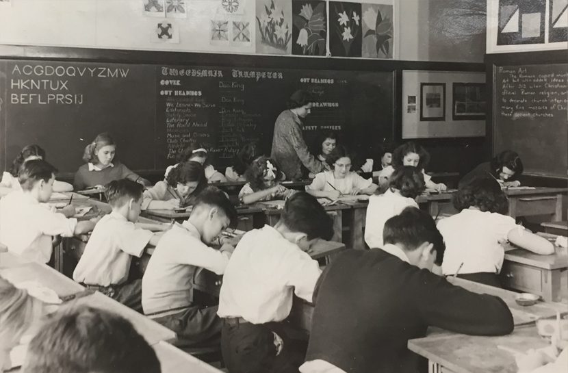 Teacher instructs her male and female students in a classroom.