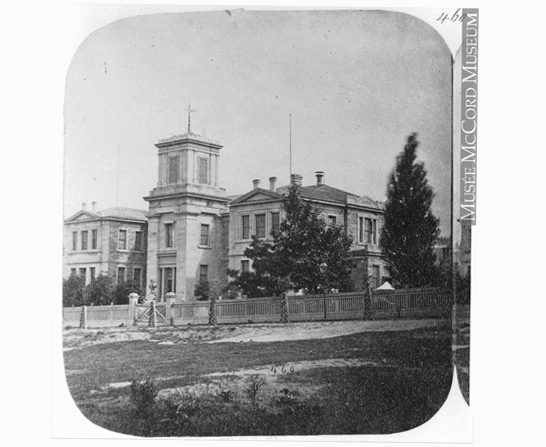 Large Georgian-style building with bell tower, fenced property and mature trees.