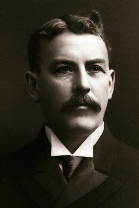Headshot of a well dressed man with a moustache.