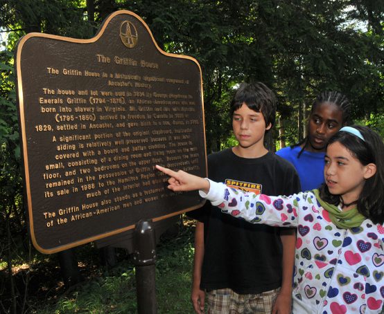 Three children reading The Griffin House historical plaque.
