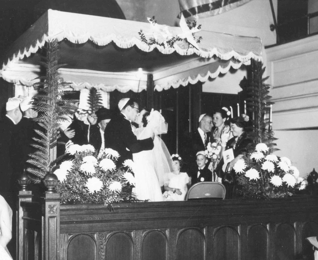 A wedding ceremony with onlookers takes place inside the Hunter Street Shul.