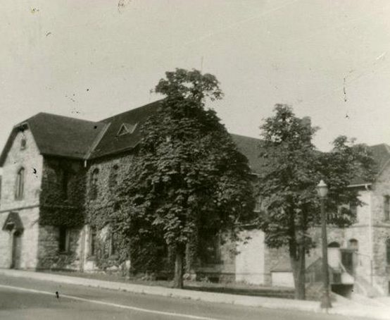 Hamilton Collegiate ivy covered two story stone building with arched windows and no roof cupola or finials.