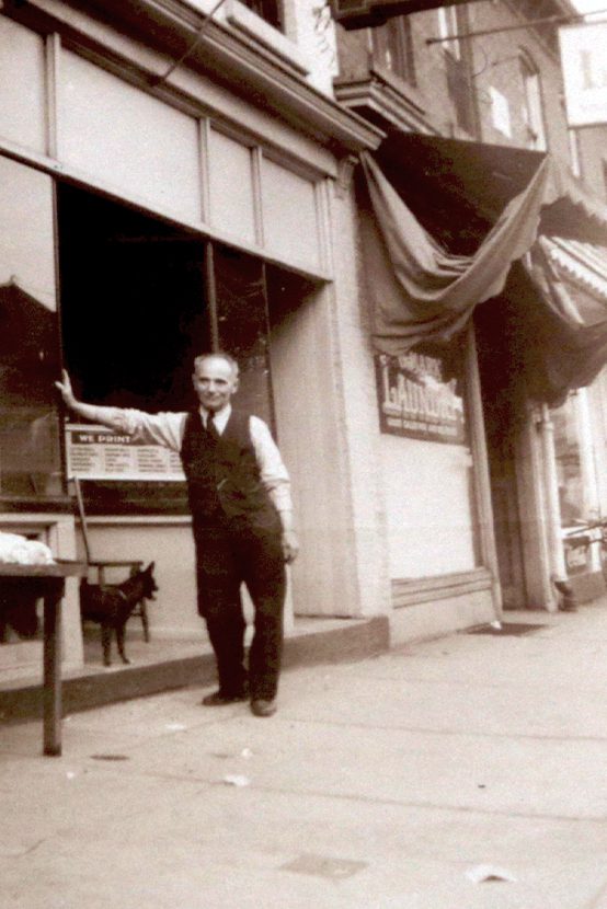 Photo of the author and publisher of 'The Jewish voice of Hamilton' leaning against the storefront with a dog.