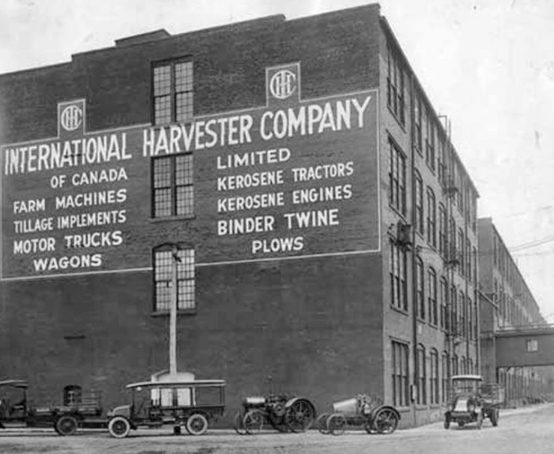 Street view of a large boxy industrial building with a large hand-painted billboard on one side.