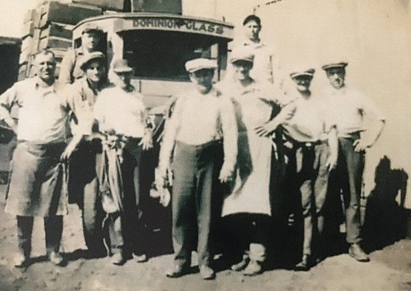 Nine workers pose in front of a Dominion Glassworks truck in the late 1920's.