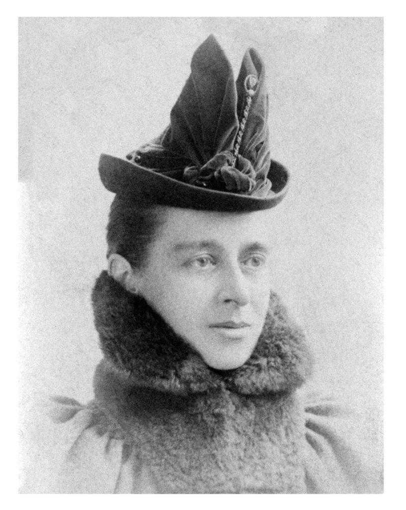 Headshot of a woman with her hair pulled back wearing a high fur collar and fashionable velvet hat.