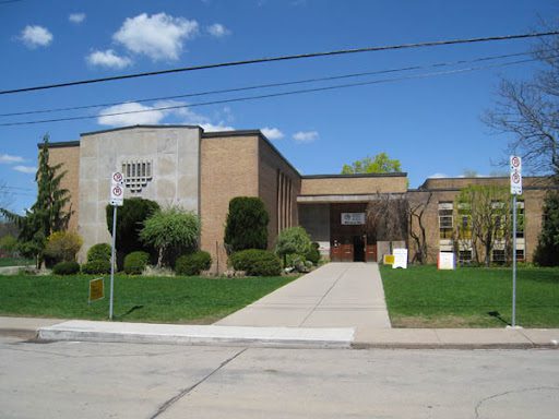 Street view of a low building with modern architectural attributes and materials.
