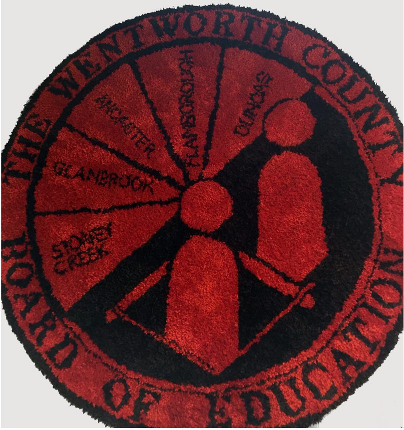 Wentworth County Board of Education visual aid in a red and black round tufted rug.