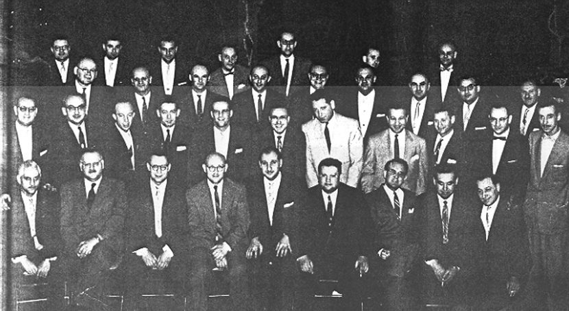 Thirty six men dressed in suits sit for group photo.