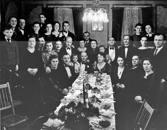 Thirty one people seated around a long dinning table pause for a photo.