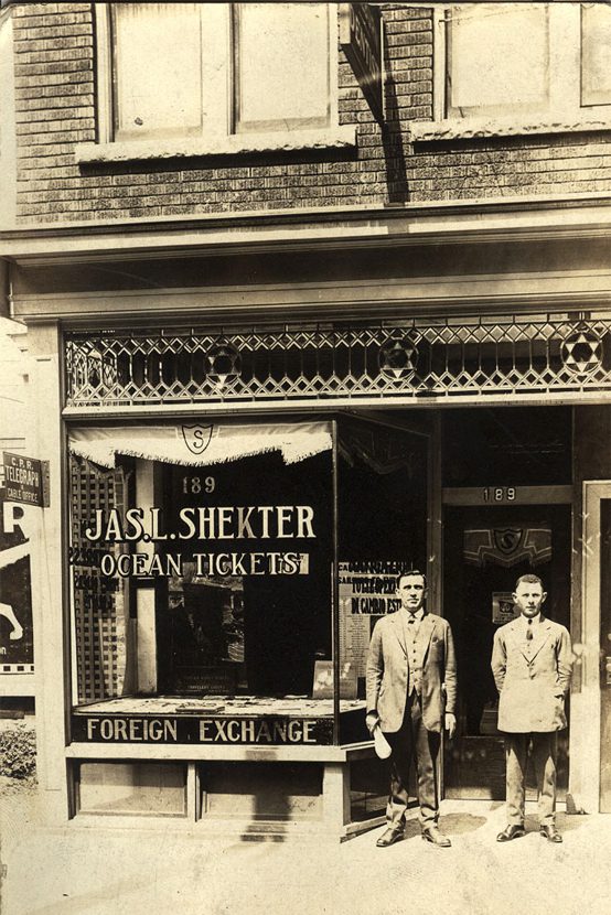 Shekter storefront with two men wearing suits in the doorway.