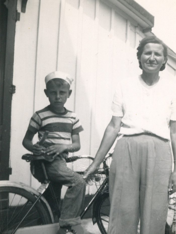 A woman standing with boy on a bike near Brightside press shed.