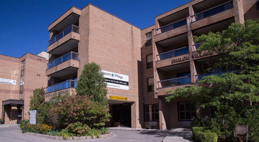 Street view of a multi level brick building with balconies Shalom Village.