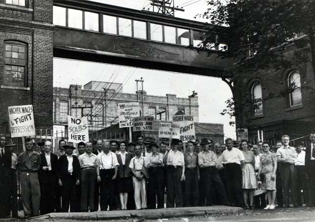 Westinghouse workers standing outside building holding strike signs.