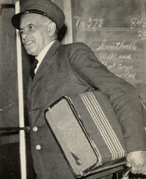 Man dressed in a Porter's uniform carrying a suitcase.