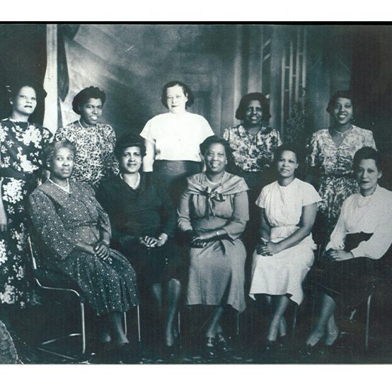 Ten women pose for a formal group photo.