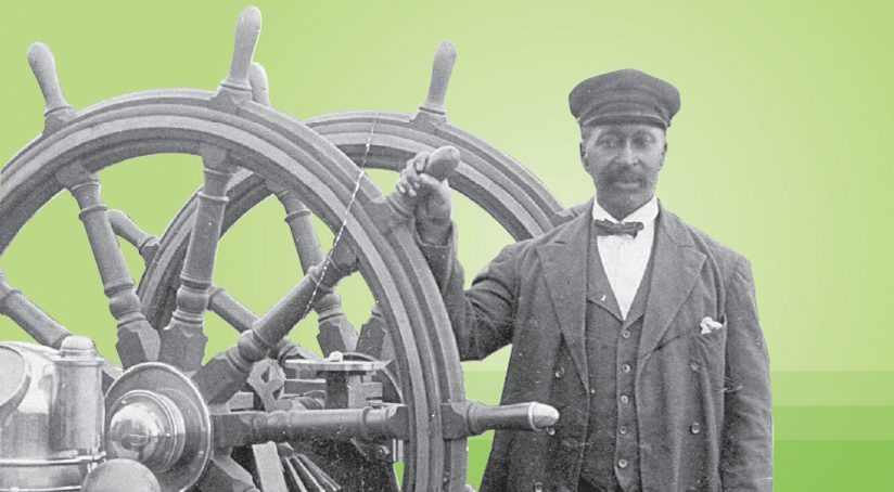 A man holding onto a ship wheel handle wearing nautical clothing and a bow tie.