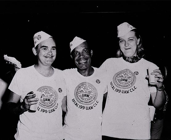 Three people with the UAW Local 199 logo printed on their white t-shirts.