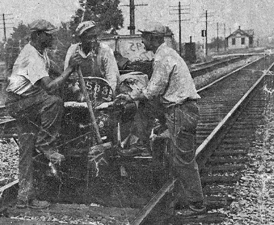 Three railroad workers repairing the tracks.