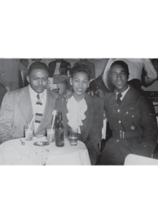 Two young gentlemen and a young woman seated at a table enjoying a night out.