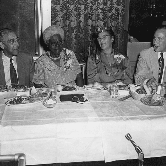 Four people formally dressed sitting at a banquet table.