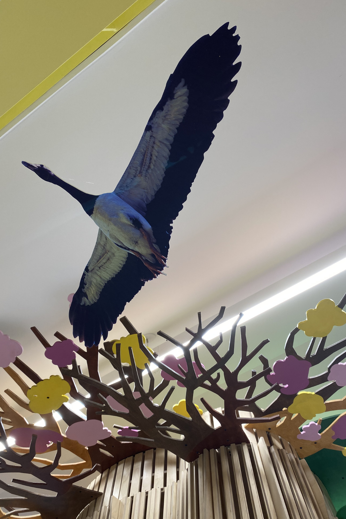 A faux bird hangs from the ceiling next to the tree canopy.