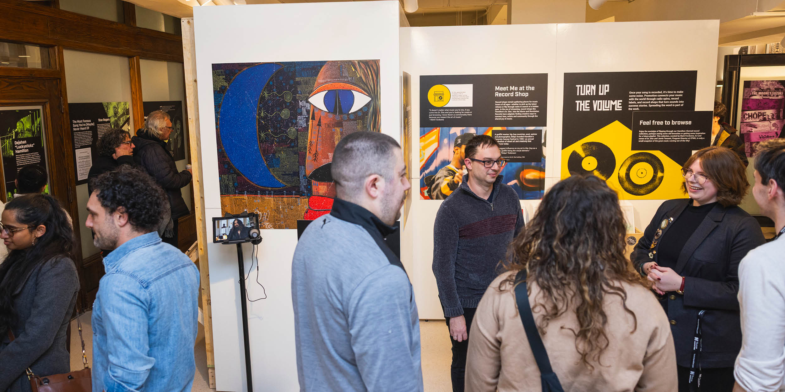A group of 5 people gathered in an exhibit space. Panels are visible behind them.