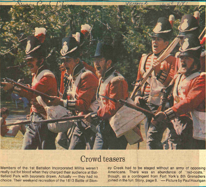 A photocopy of a newspaper article from 1981 shows 7 men in British 1812 uniform with muskets marching.