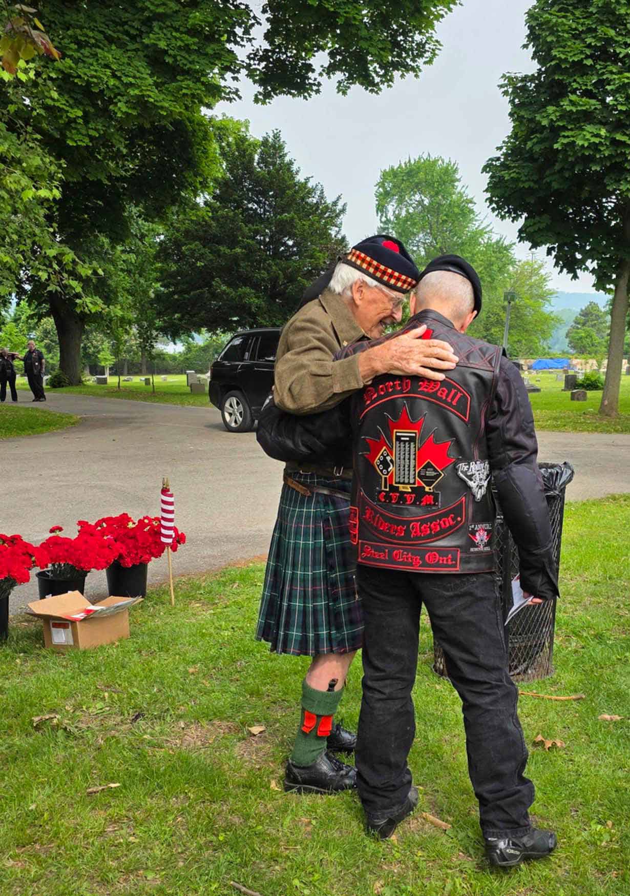 Two elderly veterans embrace in Hamilton Cemetery.