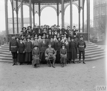 A black and white photo of a group of people in the 1940s. they are posed in front of a gazebo.