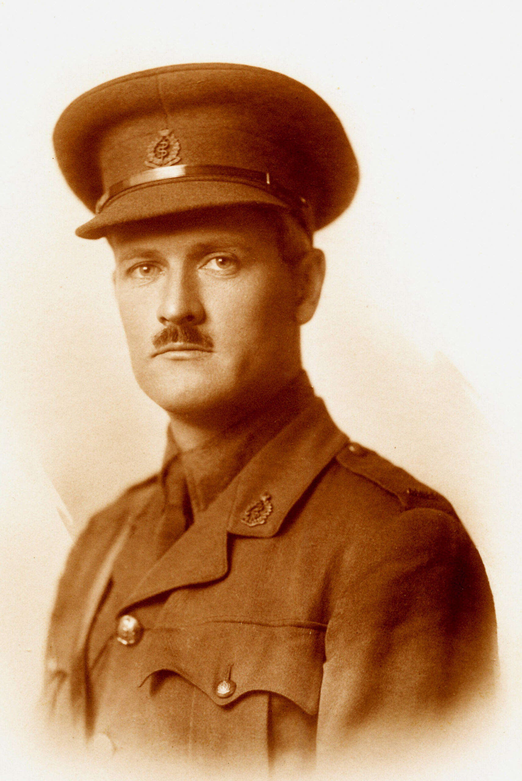 A sepia toned black and white photo portrait of a man in World War One uniform.