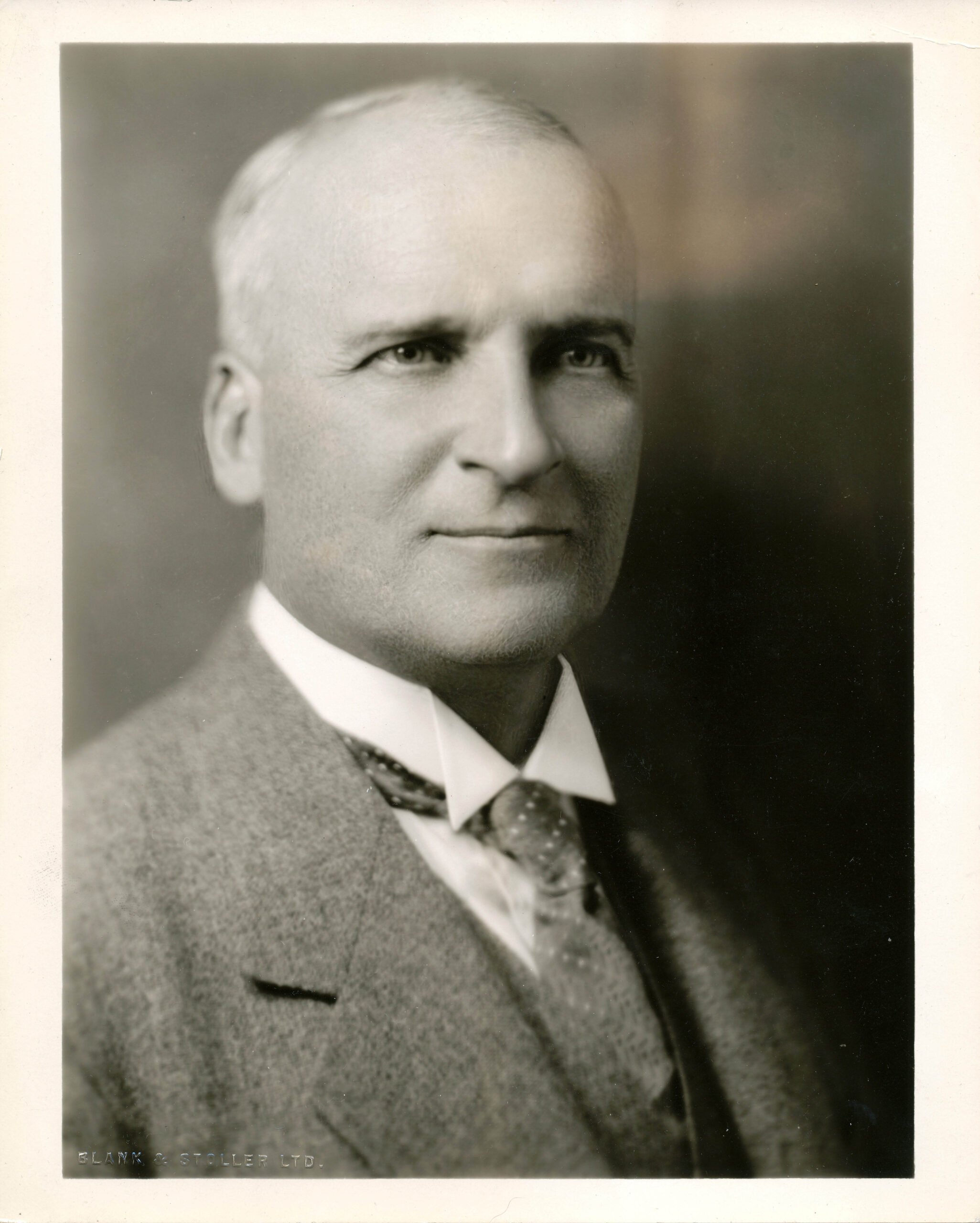 A black and white portrait of an older man in a suit.