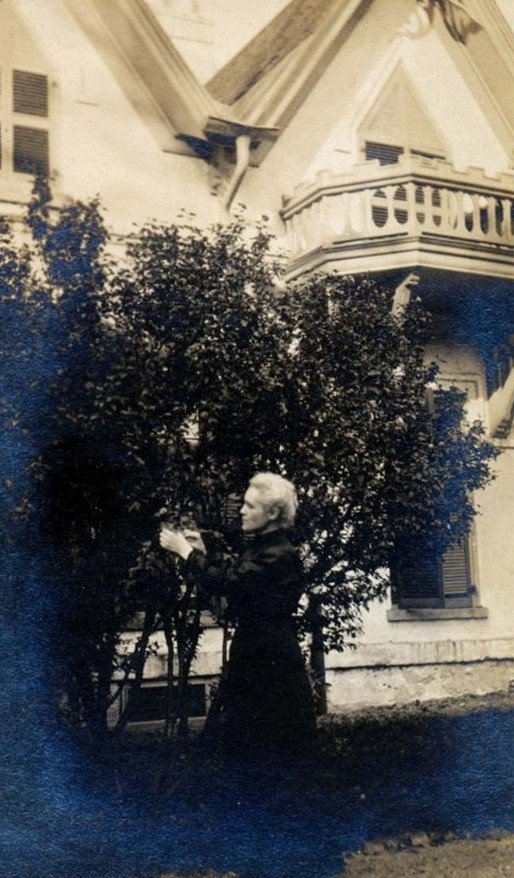 Elsie Buchanan tending shrubbery beside the house