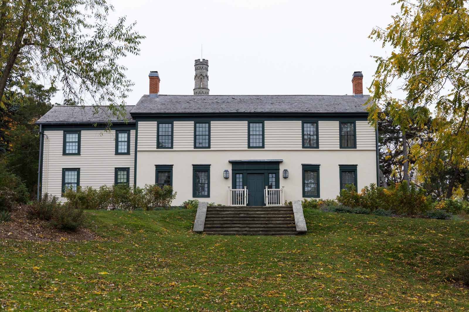 Battlefield House, a two-storey white clapboard house with dark green shutters, on a lawn scattered with fallen leaves.