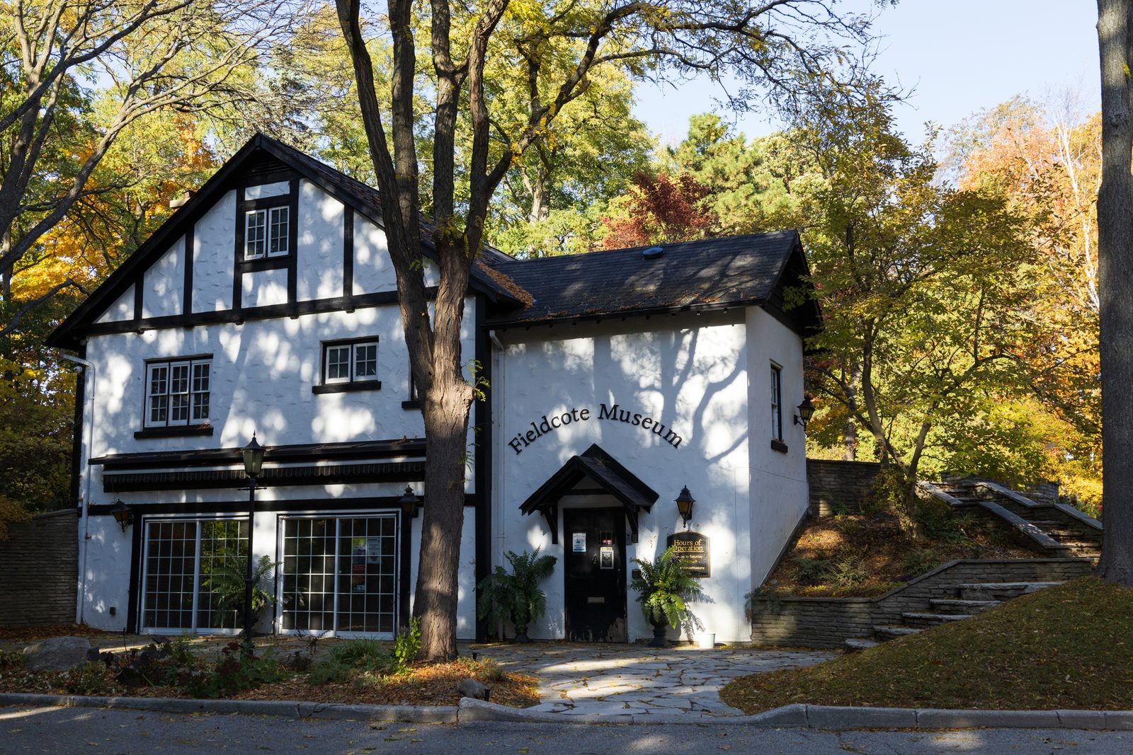 Fieldcote Museum, a white Tudor-style building with black trim, surrounded by trees in yellow and orange fall colour.